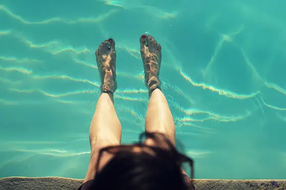 Feet dipped in cool clear turquoise water, a simple home remedy to calm burning neuropathy symptoms