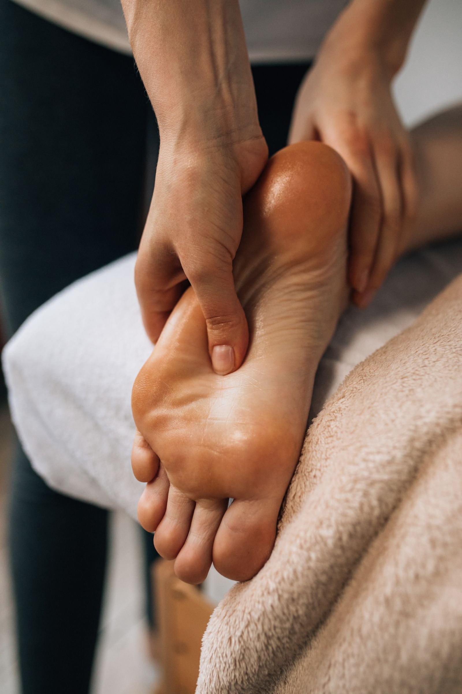 Hands slowly massaging the sole of a foot to calm burning feet before sleep