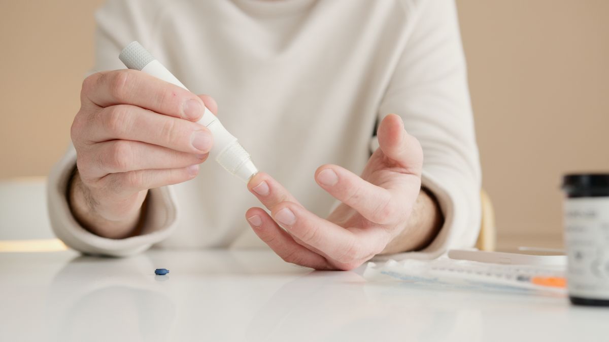 A person using a lancing device to check blood sugar with a glucose meter, an important habit for preventing diabetic neuropathy