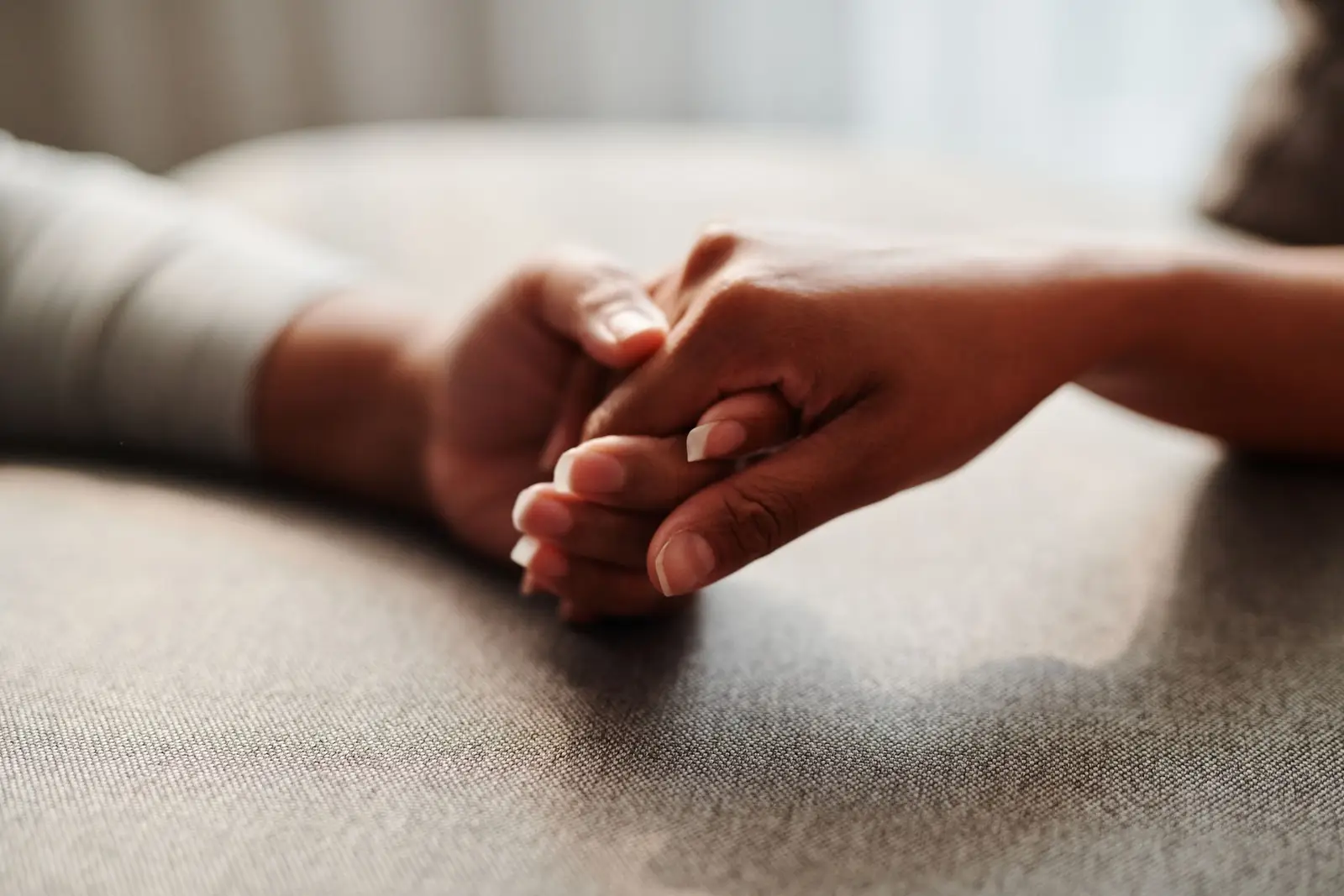 Two hands clasped together gently in a warm, softly lit room