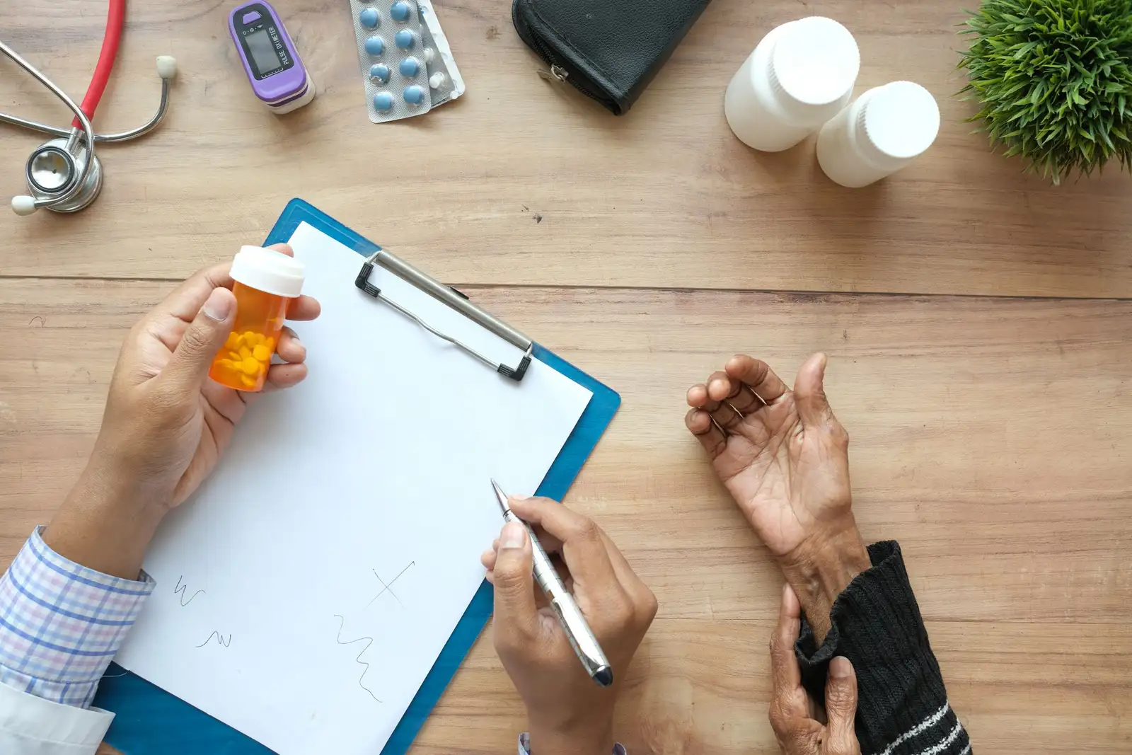 A doctor's hands holding a pill bottle beside an older patient's hand on a wooden desk, discussing a neuropathy medication plan
