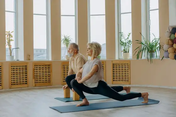 A mature couple doing gentle stretching exercises on yoga mats at home, safe movement for neuropathy in feet