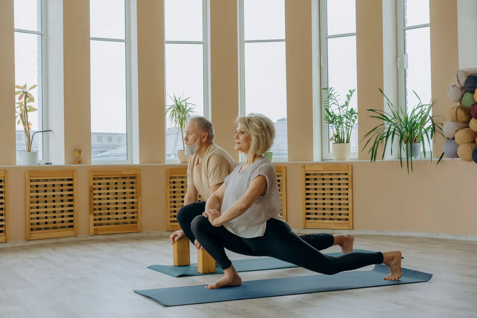 A mature couple doing gentle stretching exercises on yoga mats at home, safe movement for neuropathy in feet