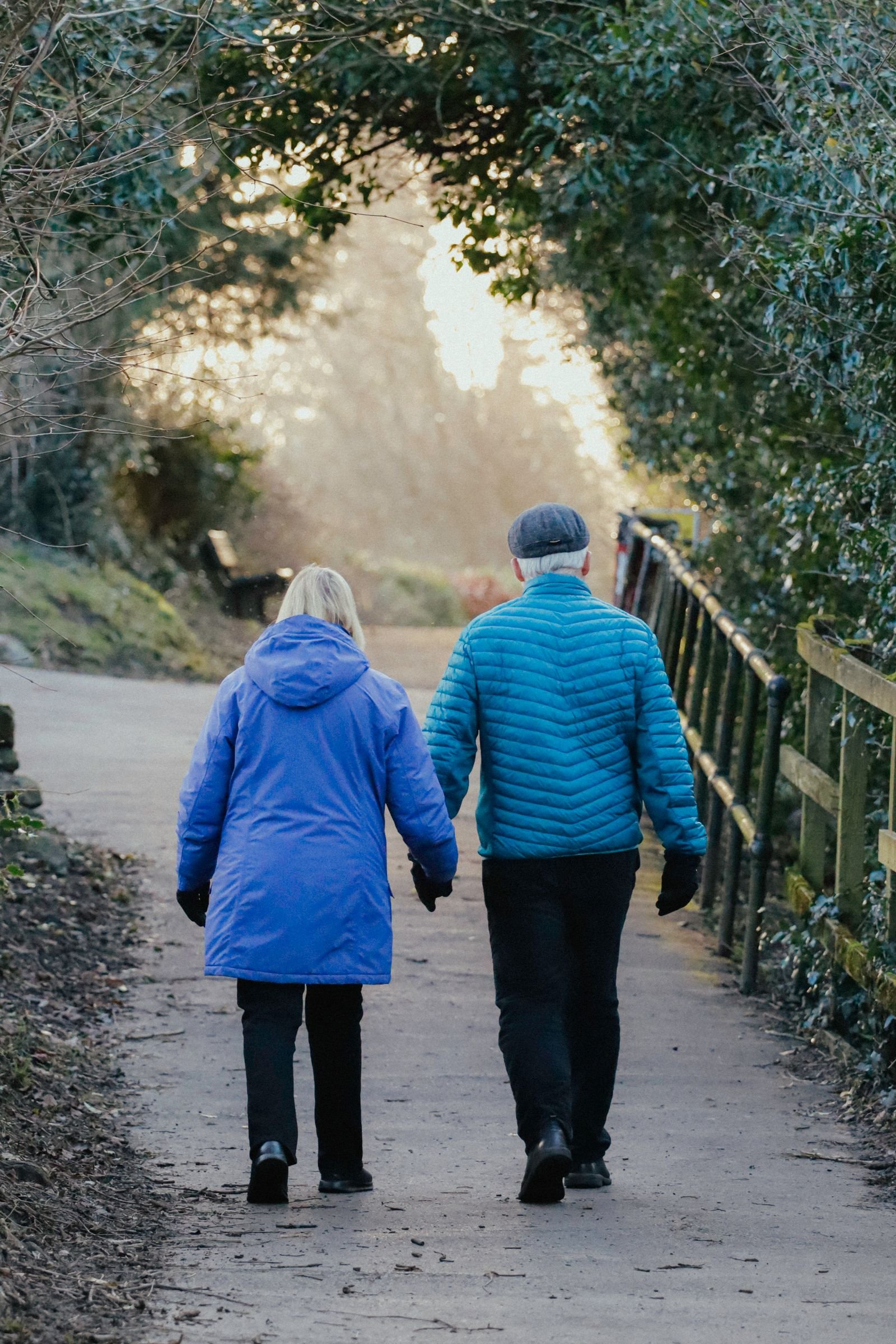 A senior couple walking together on a tree-lined path in soft evening light, a daily habit that helps calm nerve pain