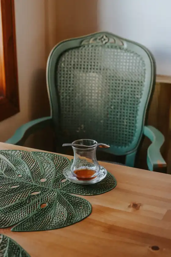 A small glass teacup of tea on a wooden table, a warm alternative evening ritual