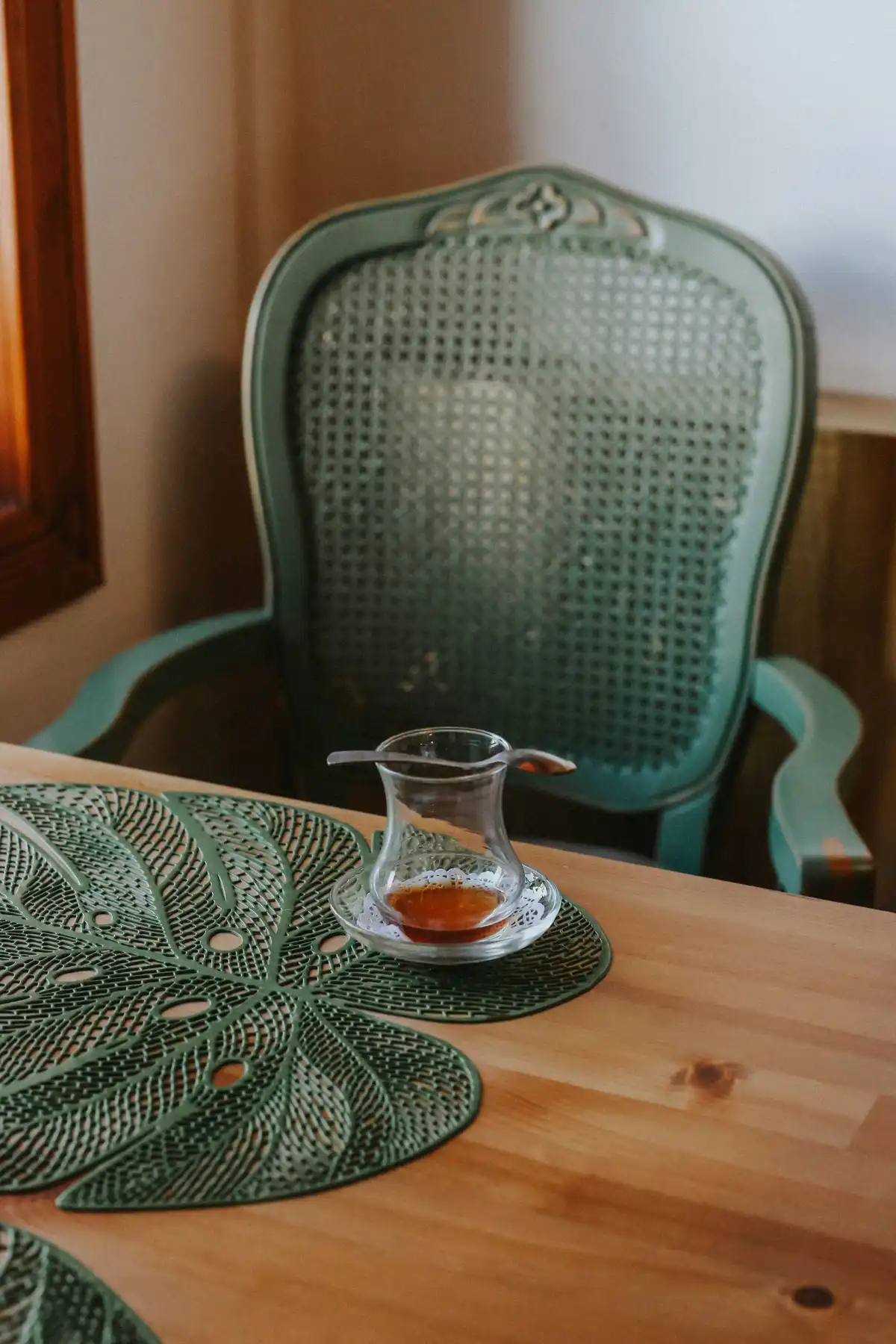 A small glass teacup of tea on a wooden table, a warm alternative evening ritual
