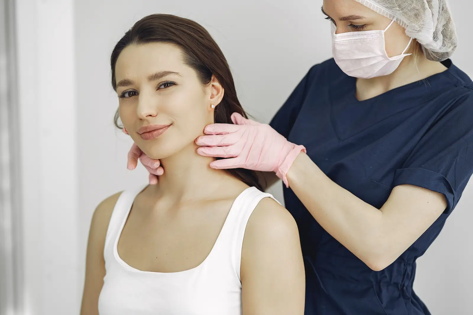 A doctor gently examining a calm patient's neck and throat during a routine thyroid check