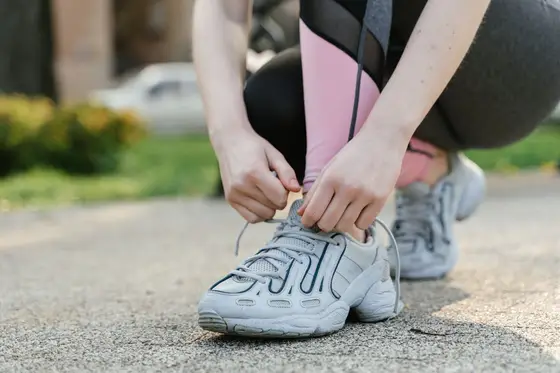 A person tying the laces of cushioned walking shoes